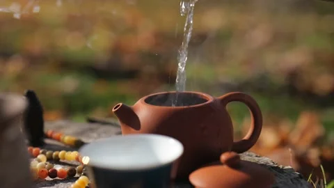 Close-up. boiling water is poured from a thermos into a clay teapot Stock Footage 229858600