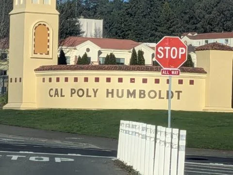 Close-up of bold yellow Cal Poly Humboldt sign with campus in background Stock Photos