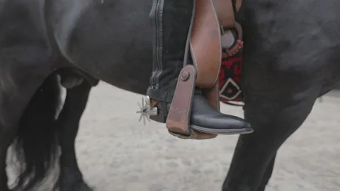 Close up of the boot of a cowboy riding a black horse Stock Footage 159614710