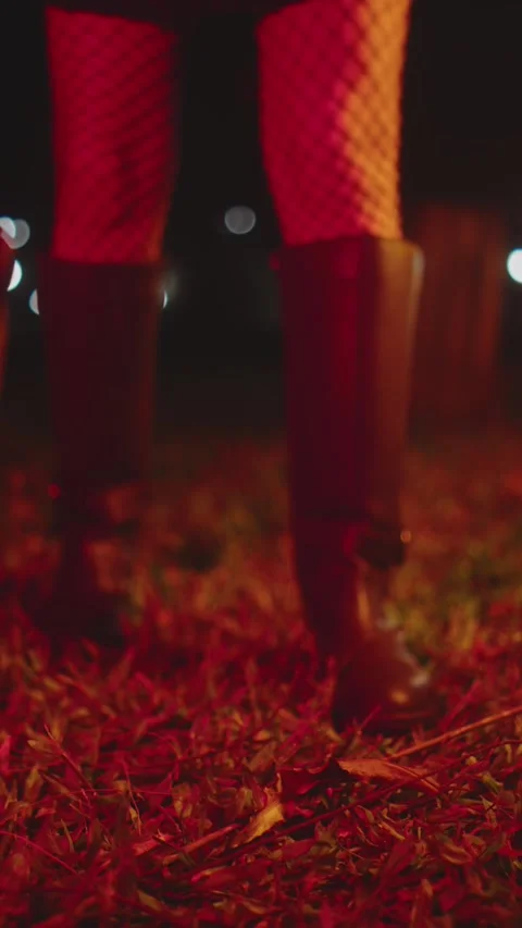 Close-up of boots standing on grass at night with red lights Stock Footage 327832491