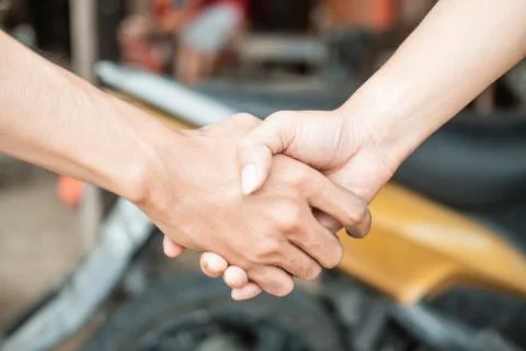Close up of both hands shaking hands against the background of the motorbike Stock Photos