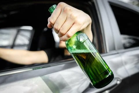 Close-up of a bottle of beer in the driver hand in window car. Alcohol driving Stock Photos