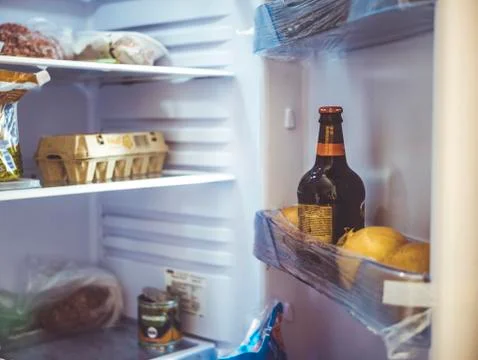 Close up bottle of beer in opened fridge Stock Photos