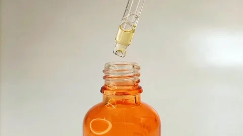 Close up bottle pipette dropper liquid yellow-orange vitamin c or retinol serum Stock Footage 284535069