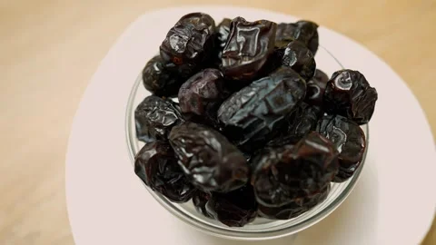 Close-up of a bowl of fresh dates on a dark plate with a golden spoon Stock Footage 320727836