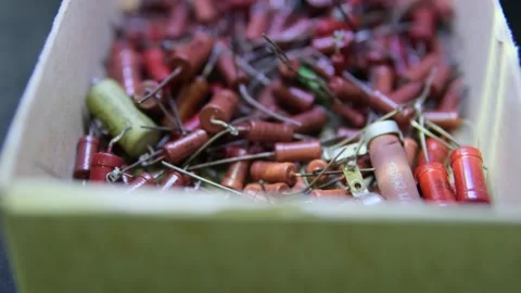 Close-up of a box filled with various vintage electronic capacitors, featuring Stock Footage 302353016