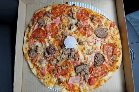 Close up box of Thin crust pizza topped with ham pepperoni and sausages Stock Photos