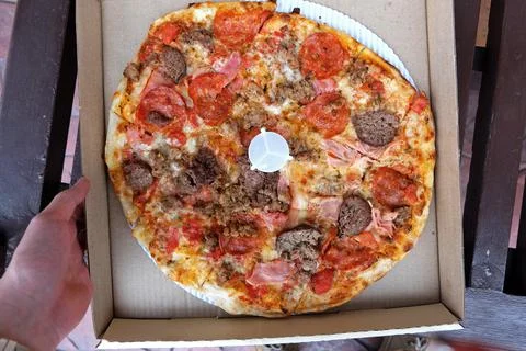 Close up box of Thin crust pizza topped with ham pepperoni and sausages Stock Photos