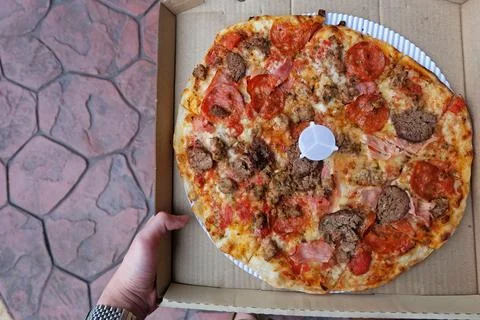 Close up box of Thin crust pizza topped with ham pepperoni and sausages Stock Photos