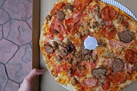 Close up box of Thin crust pizza topped with ham pepperoni and sausages Stock Photos