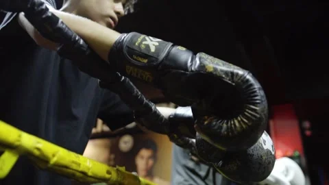 Close up of boxer resting gloved arms on boxing ring ropes during training Stock Footage 340923940