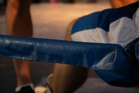 A close-up of a boxing ring with a boxer sitting in the background at a gym Stock Photos
