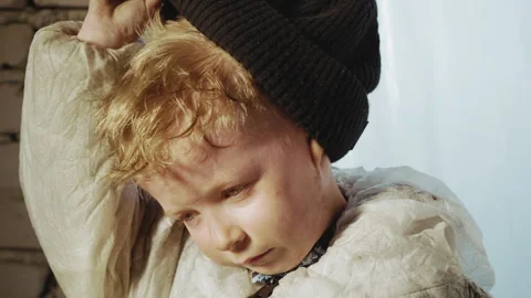 Close Up of Boy Adjusting Beanie in Dirty Suit Inside Abandoned Building 動画素材 329464282