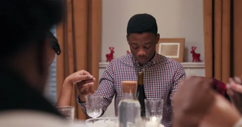 Close-up of boy of African appearance sitting at table with friends and praying Stock Footage 218266856