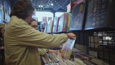 Close up of boy and girl pulling out vinyl records at Homer's Record Store Video stock 155436520