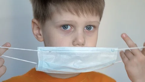 Close up of a boy with blue eyes putting a mask on his face Stock Footage 128055432