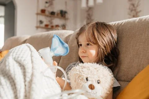 Close-up of a boy doing inhalation at home sitting on the couch with a nebulizer Stock Photos