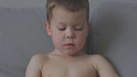 Close-up of boy face sits on couch capturing essence of carefree childhood and Stock Footage 284673420