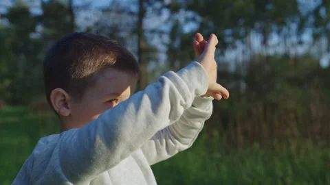 Close-up of a boy looking toward sunlight through his hands Video stock 197098929
