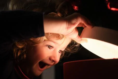 Close-up boy opening magic gift box near Christmas tree Stock Photos