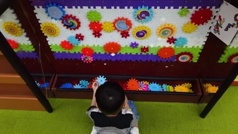 Close up of a boy playing assembling gears so they connect together Stock Footage 275312384