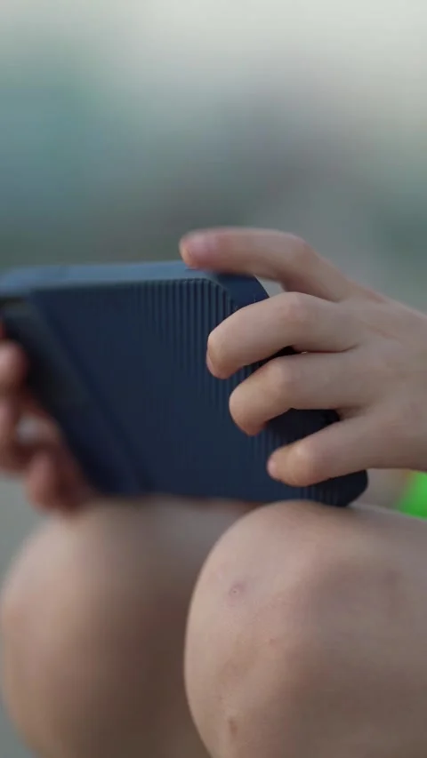 Close-up of a boy playing on a smartphone outdoors. Video stock 342570686