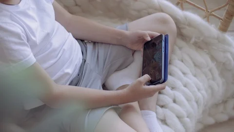 Close up boy playing on a smartphone sitting in the chair at home. Stock Footage 111553226