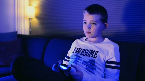 Close up of boy playing video game and using a controller while sitting at home Stock Footage 98849505