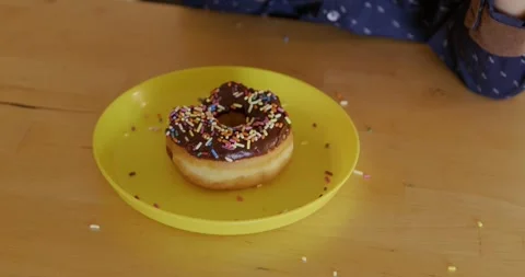 Close-up boy reaching donut on plate. Soft natural light highlights chocolate 스톡 동영상 326177197