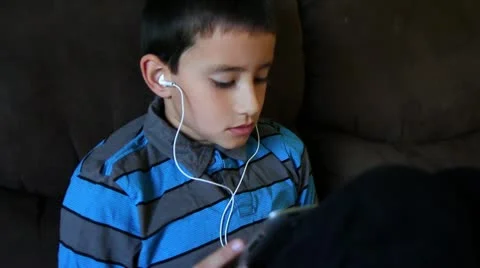 Close up of boy reading on tablet wearing headphones Stock Footage 12296838