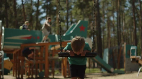 Close up of a boy riding a chain swing at an outdoor park playground. Child.. Stock Footage 343208163