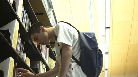 Close-up of  boy searching book on self Stock Footage 76536915