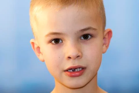 Close-up of boy smiling with missing front milk tooth over light background.  Stock Photos