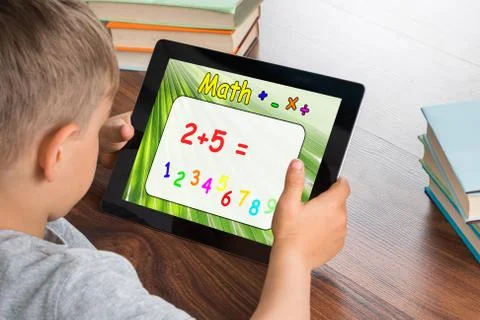 Close-up Of Boy Solving Math Problem On Digital Tablet In Classroom Stock Photos