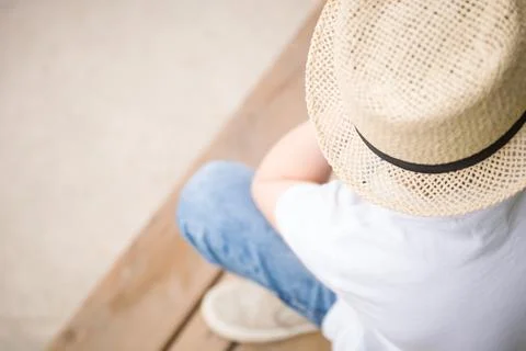 Close-up of a boy in a straw hat sitting on the wooden bench Stock Photos