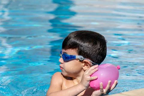 Close-up of a Boy with swimming goggles throwing a water balloon. Stock Photos