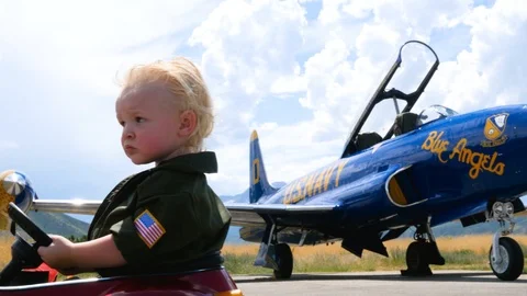 Close up of boy in the uniform as he drives toy car near plane Video stock 116736147