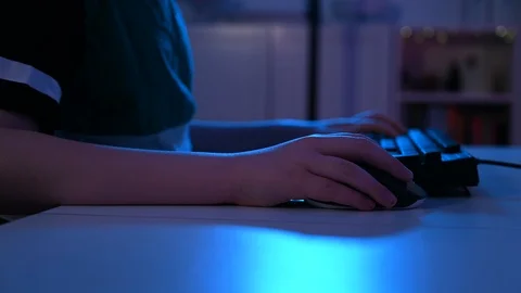 Close up of boy using a computer mouse at night while playing video games Stock Footage 100787855