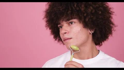 Close-up a boy, using a jade facial roller along the jaw line Stock Footage 269136907