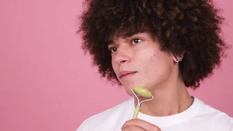 Close-up a boy, using a jade facial roller along the jaw line Stock Footage 269362913
