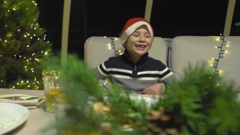 Close-up of a boy wearing a santa hat laughing on the couch for the new year. Stock Footage 220080560