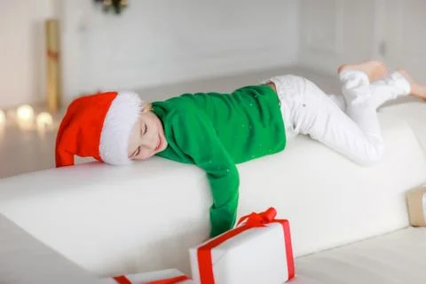 Close-up of a boy on a white sofa surrounded by gift boxes in white packaging Stock Photos