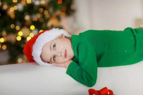 Close-up of a boy on a white sofa surrounded by gift boxes in white packaging Stock Photos