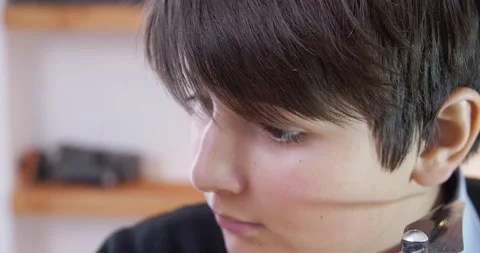 A close-up of the boy's face he twists a part of the robot he assembled with a Stock Footage 147411575