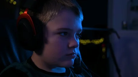 Close up of boy's face while wearing gaming headset and playing video games Stock Footage 100790381
