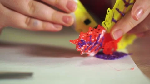 Close-up of a boy's hand create a plastic flower. He uses a 3D pen. Stockbeeldmateriaal 100388035