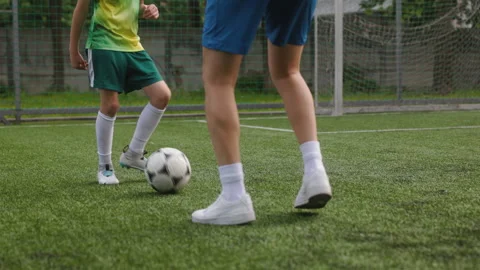 A close-up of a boy's legs as he practices passing with his coach on an Video stock 279656682