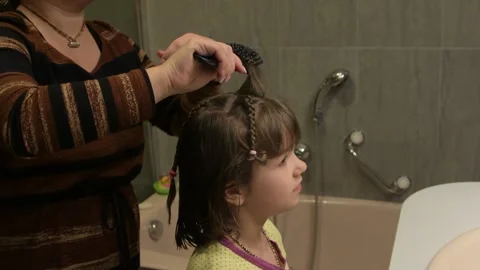 Close up of braid hairstyle being made on child head at home. Video stock 331249414
