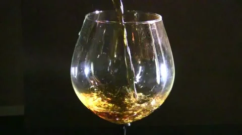 Close up of brandy being poured into snifter against black background Stock Footage 57640183
