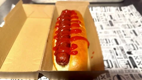 Close up of bratwurst hot dog in bread bun with ketchup on top in packaging Stock Footage 345676662
